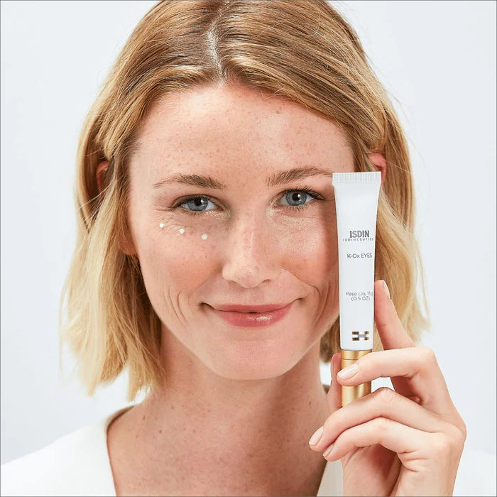 Woman holding ISDIN Isdinceutics K-Ox Eyes eye cream with dots under one eye