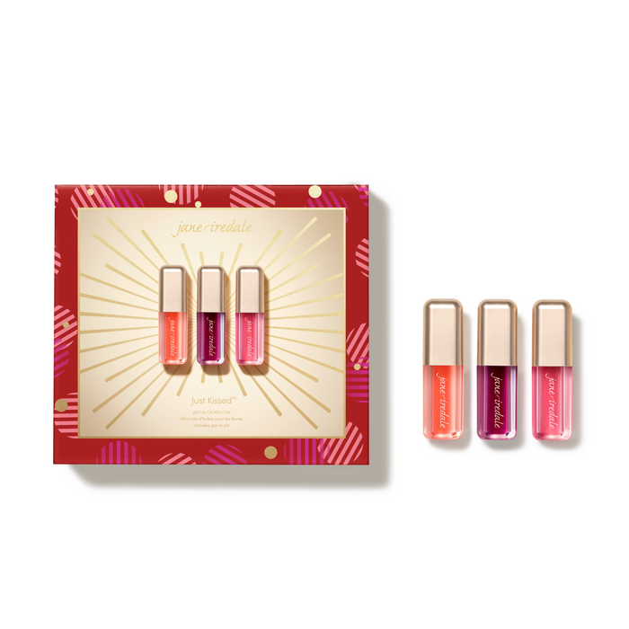 Jane Tredeale Just Kissed lip gloss set featuring three individual tubes of lip gloss in coral, pink, and purple shades, displayed next to their red and gold gift box on a clean white background.