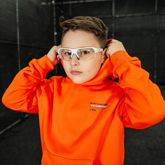 Youth model wearing orange Max Clark youth hoodie