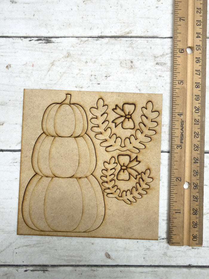 Unfinished stacked pumpkin kit pieces beside a ruler showing the approximate size of the wood craft
6