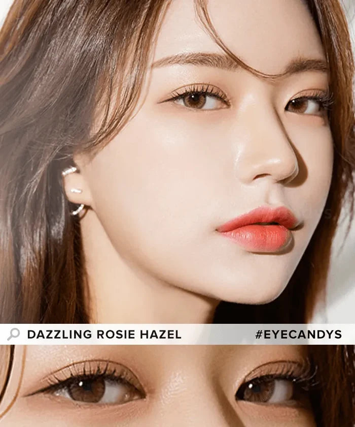 Close-up of a woman with fair skin, glossy coral lips, and light brown eyes wearing Olola Dazzling 1-Day Rosie Hazel (10pk) color contacts by Olola. She has long brown hair and looks slightly to the side. Text: “DAZZLING ROSIE HAZEL #EYECANDYS.”.