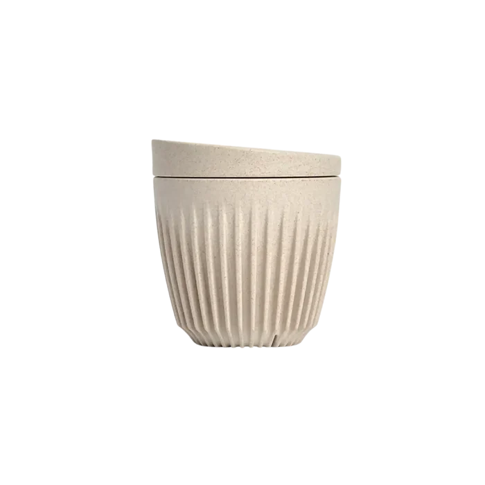 Beige ceramic pot with ribbed texture on a white background