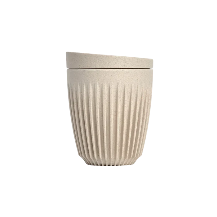 Beige textured ceramic cup with lid on a white background
