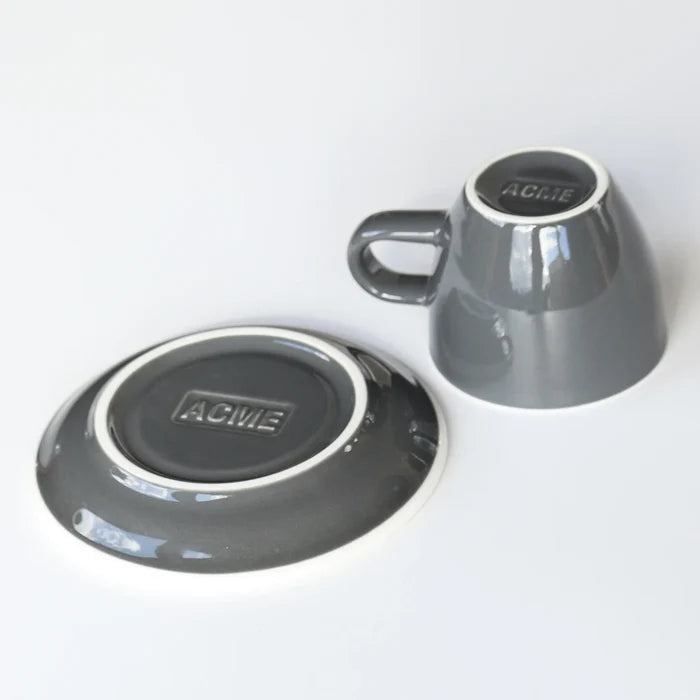 ACME grey ceramic cup and saucer on a white background