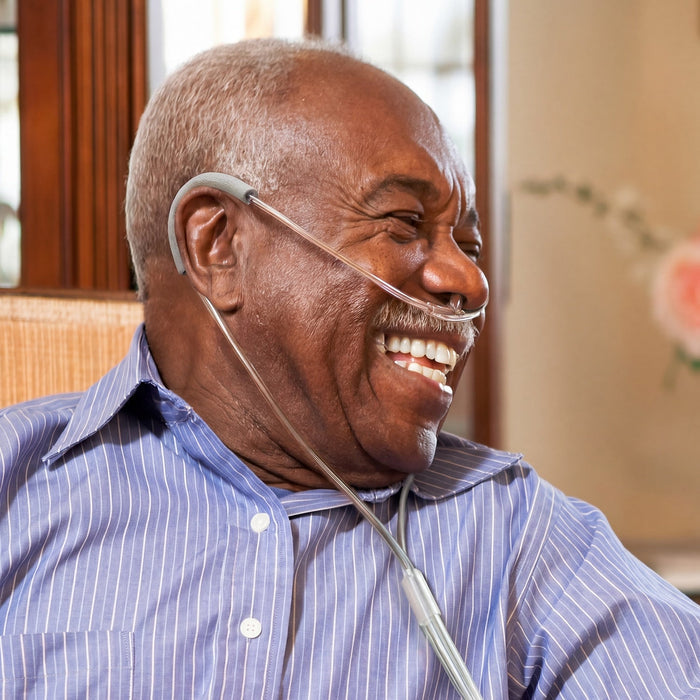 Man wearing an oxygen tank with over the ear wraps smiling indoors.