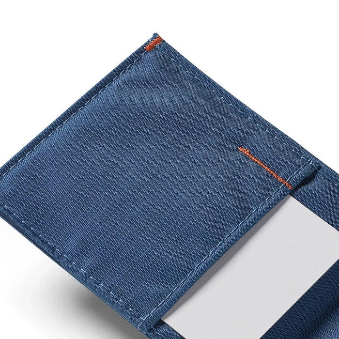 The ALLETT Sport Wallet in RFID-blocking indigo blue nylon features a minimalist design with an orange triangular logo on the corner, shown against a white background.