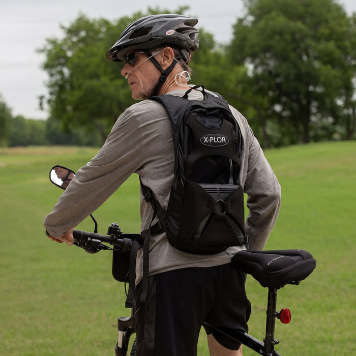 Man Riding a Bike with an X-Plor Oxygen Concentrator Backpack