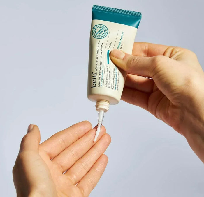 Hand squeezing moisturizer cream from a tube onto palm, skin care lotion application