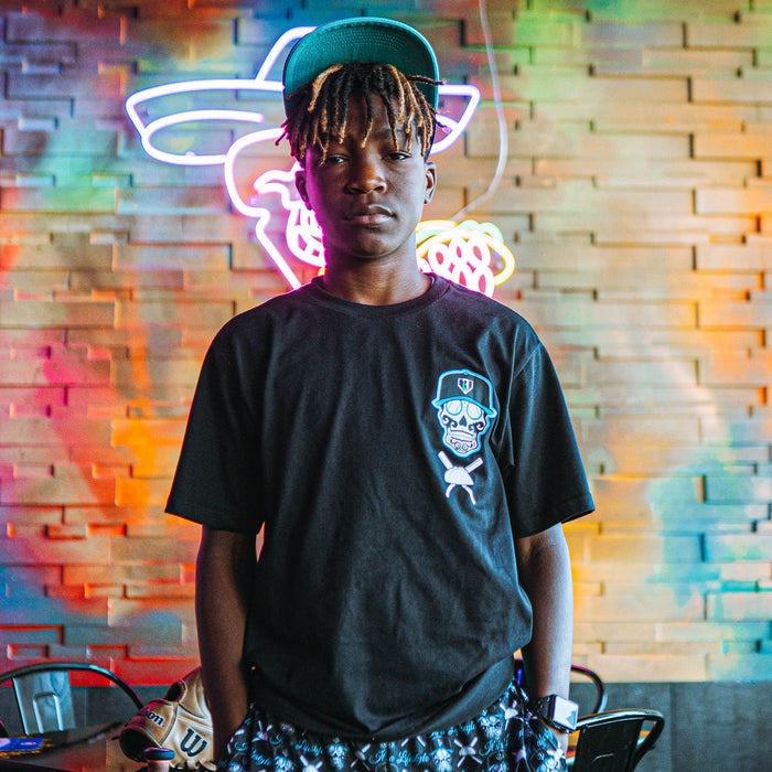 Person wearing a black t-shirt with a skull design in front of a colorful neon sign