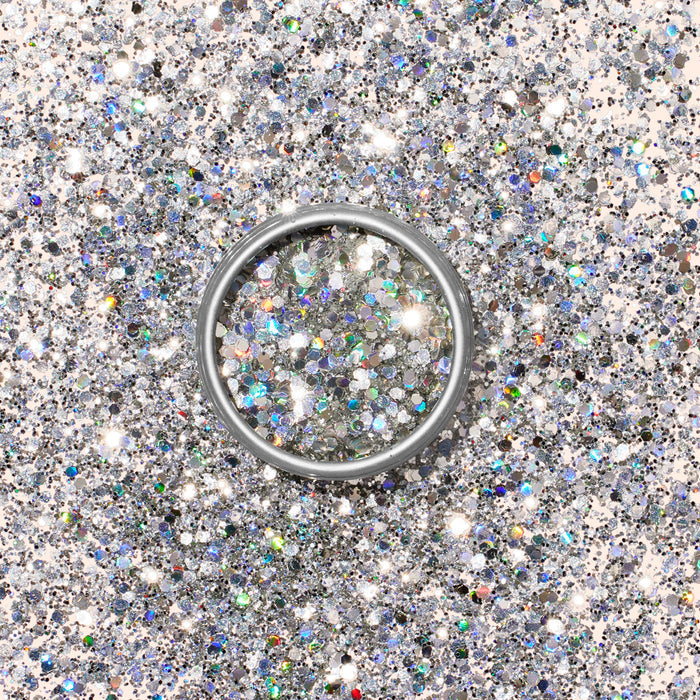 A silver ring rests on a surface dusted with Manucurist Biodegradable Holo Glitter, reflecting light for a dazzling, eco-friendly effect that’s perfect for nail art inspiration.