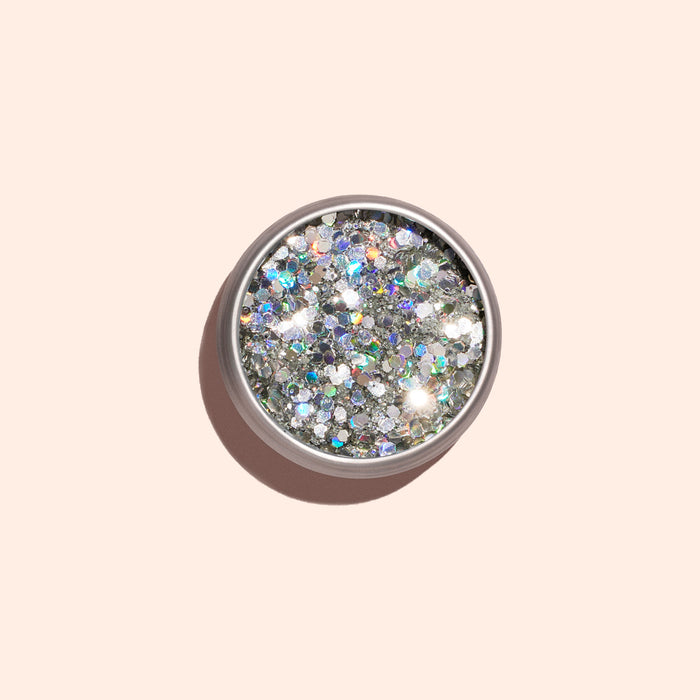 A round container of Manucurist Biodegradable Holo Glitter, seen from above on a light beige background with a soft shadow—ideal for adding eco-friendly sparkle to your next nail art design.
