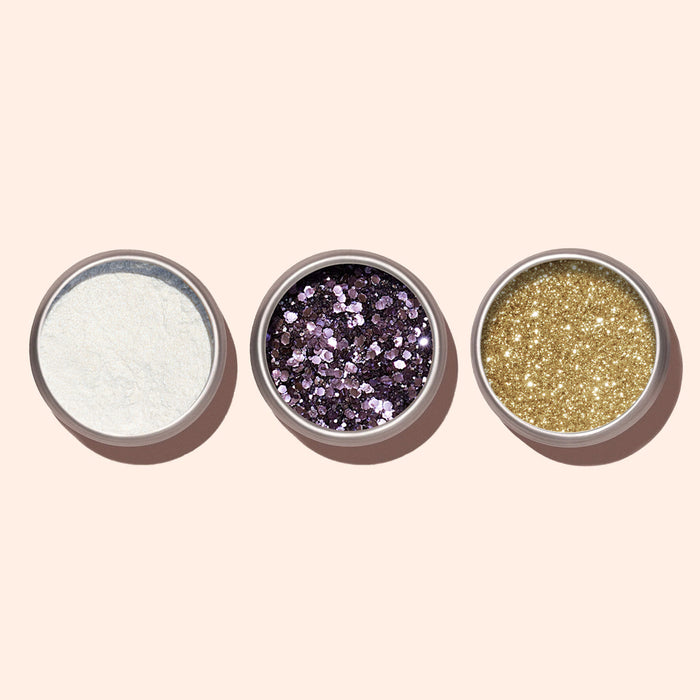 Three small round containers hold white powdery glitter, chunky purple glitter, and fine gold glitter—ideal for manicures or pairing with Manucurist's Blue Glazed Powder.