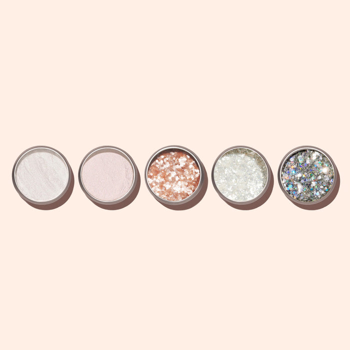 Five round containers of Manucurist’s Blush Biodegradable Glitter, featuring various shimmery and glittery powders—including a pale pink ideal for nail art—are arranged in a row on a light beige background.