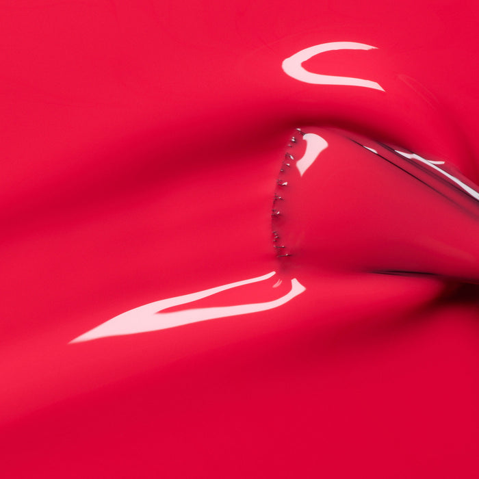 A shiny, stretchy pink-red surface—reminiscent of Manucurist's Bougainvillea gel polish—is pulled from behind, creating smooth curved folds with highlights that reflect light.