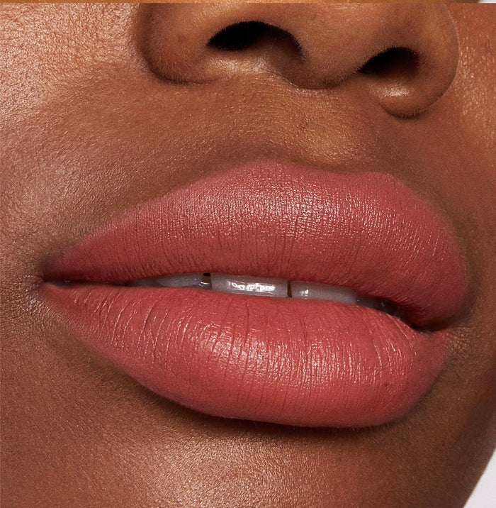 Lips wearing ColourPop Lippie Stix Brink, a warm rosy terracotta nude in a soft‑matte finish, shown in a close-up to highlight smooth, even coverage and creamy texture.