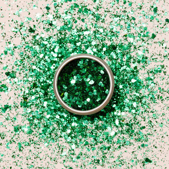 A round metal container of Manucurist Cactus Biodegradable Glitter sits on a surface, surrounded by scattered green glitter—perfect for creative nail art designs.
