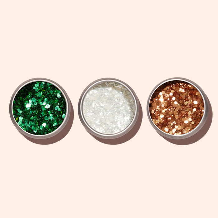 Three round metal tins of Manucurist Copper Biodegradable Glitter are arranged side by side on a light beige background. The green, white, and gold glitters are perfect for nail art.