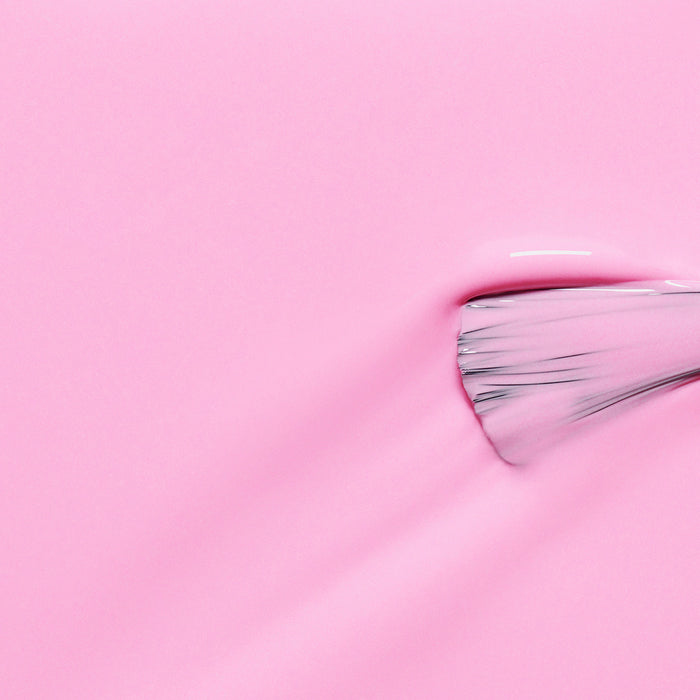 A close-up of a Manucurist paintbrush spreading their glossy neon pink "Candy" nail polish, revealing visible bristles and vivid texture on the right.