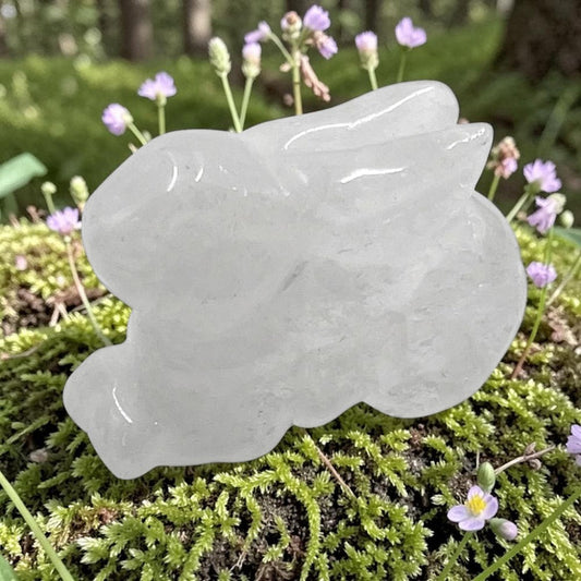 Clear quartz bunny on a green mossy surface with small purple flowers