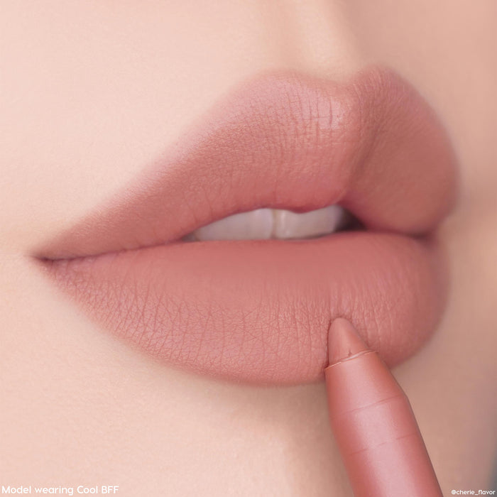 Cool Besties ColourPop Lippie Pencil lining soft matte lips in a cool-toned nude shade, the tip gliding along the lower lip for precise definition in a close-up studio beauty shot.
