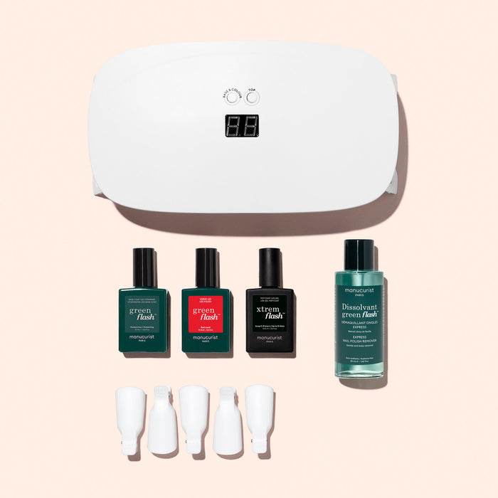 The Manucurist Discovery Kit—featuring a white UV lamp, three polishes, remover, and four clips—is displayed on a pale pink background, giving you all you need for an ultra-glossy gel manicure.