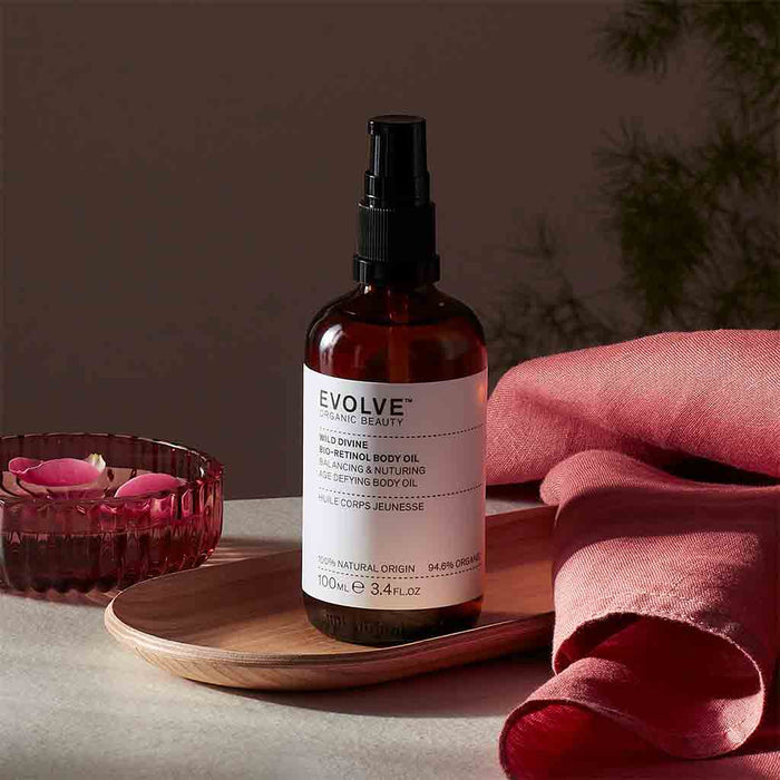 Evolve Wild Divine Body Oil 100 ml. Öljypullo ja ruusun terälehtiä