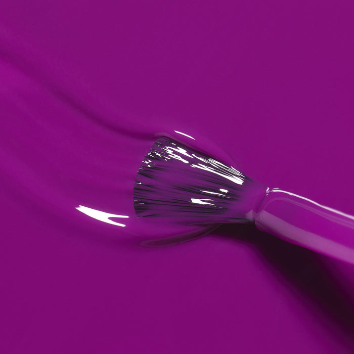A close-up of the Manucurist Fizz brush applying glossy, bright purple nail polish with magenta undertones on a smooth surface.