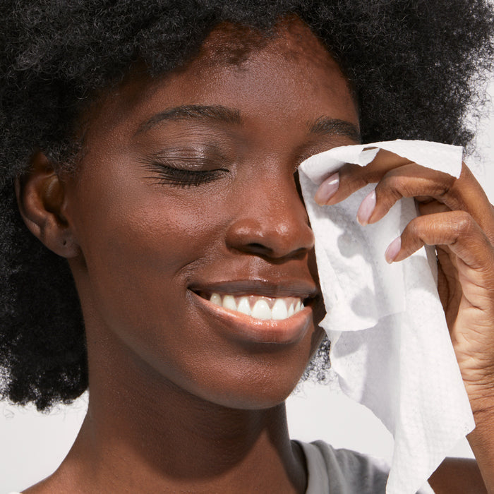 Model wiping eyes with face wipe.