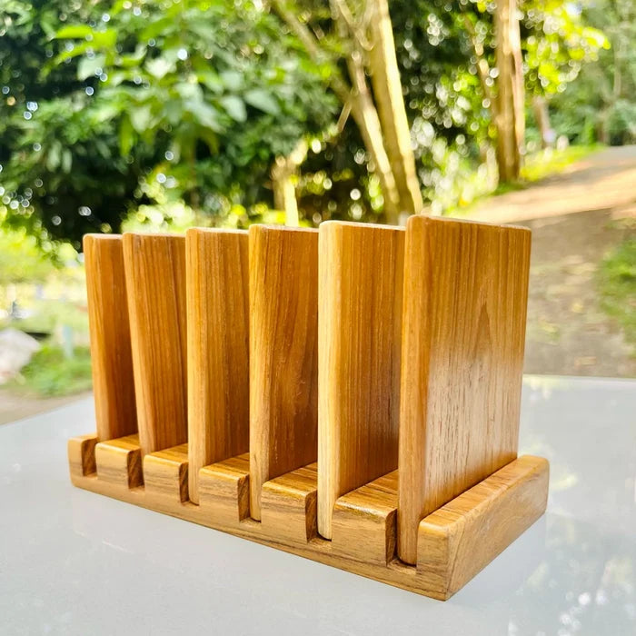 Handmade 7-piece golden teak wood coaster set with a vertical storage rack, featuring natural wood grain and water-resistant coating.