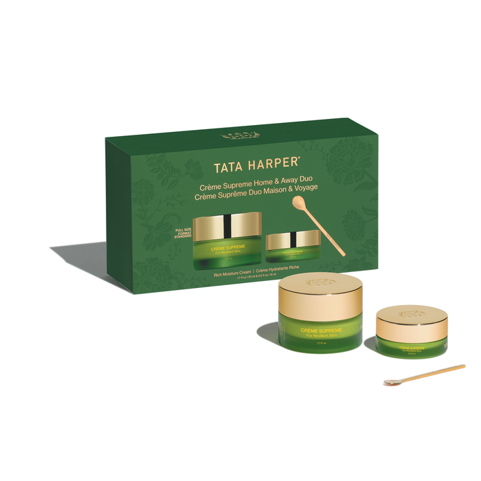 Tata Harper Crème Suprème Home & Away Duo gift set, featuring a dark green box, two green and gold cream jars, and two wooden spoons on a clean white background.