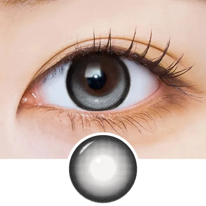 Close-up of an eye with long lashes wearing EyeCandys i-Sha Dekame Kiss Me 1-Day Cloudy Ring Grey colored contact lenses, showing the lens design pattern