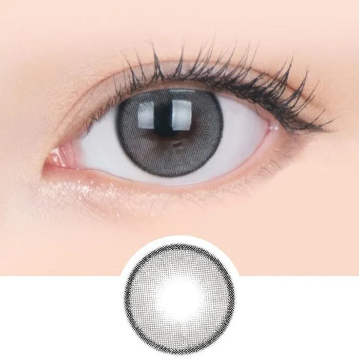 Macro shot of an eye wearing the i-Sha Jadey Mono Grey prescription colour contact lens, showing the multi-colored detail and natural effect on dark brown eyes, with clean eye makeup. At the bottom is the pattern of the colored lens design, showing the dotted detail and pigmentation.