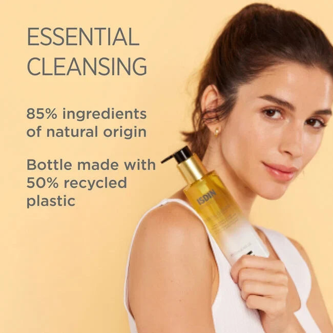Woman holding ISDIN Essential Cleansing bottle; 85% natural origin, 50% recycled plastic