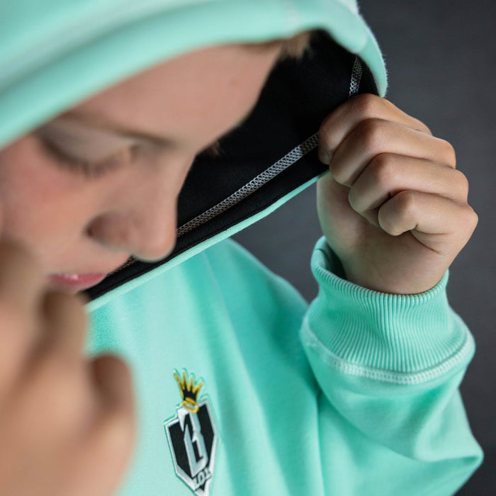 Youth model wearing teal hoodie with "King Of JUCO" design