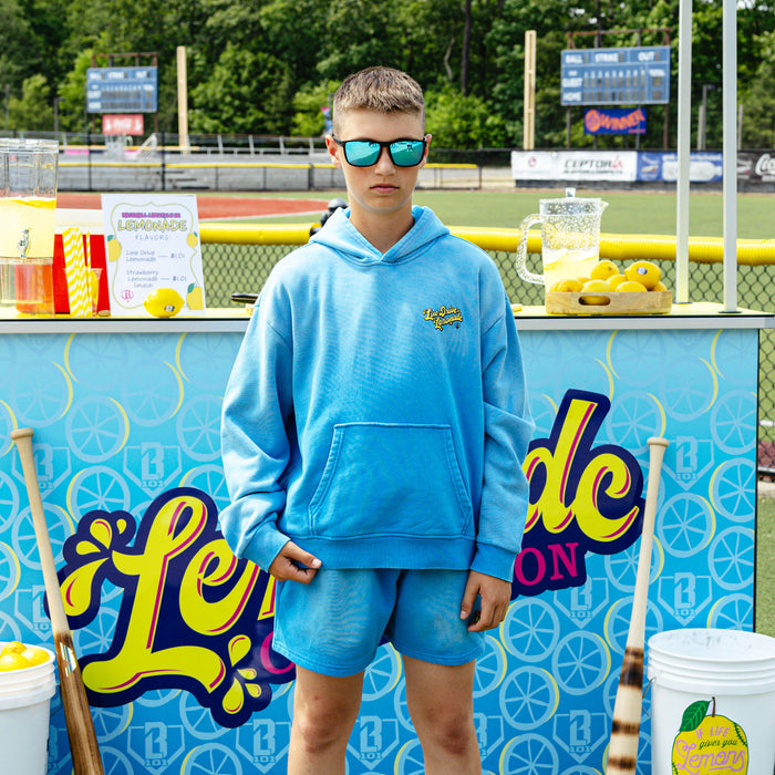 Youth model wearing blue youth hoodie with "Lemonade Cup" design