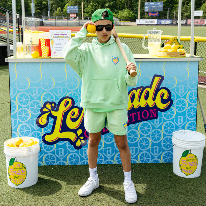 Youth model wearing green youth hoodie with "Lemonade" design