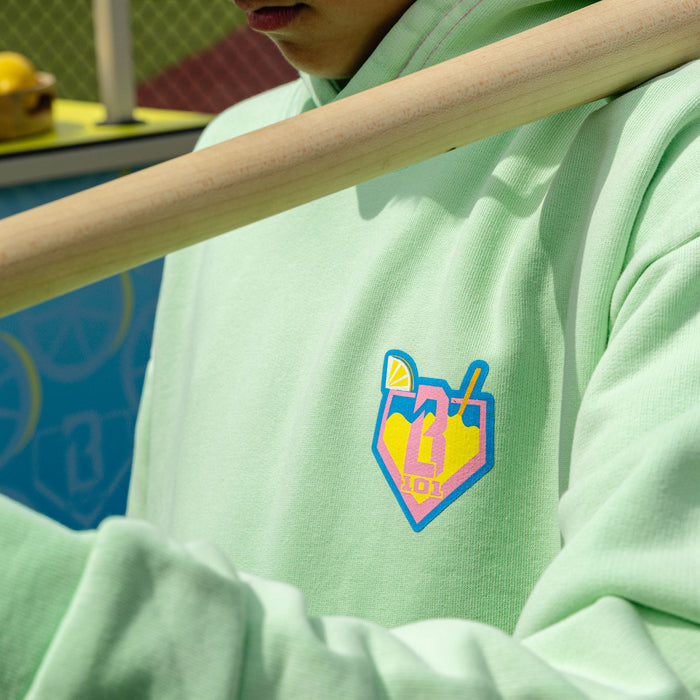 Youth model wearing green youth hoodie with "Lemonade" design