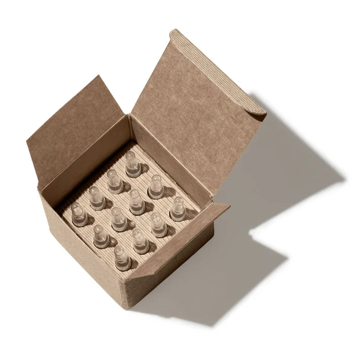 Open cardboard box containing small clear bottles on a white background
