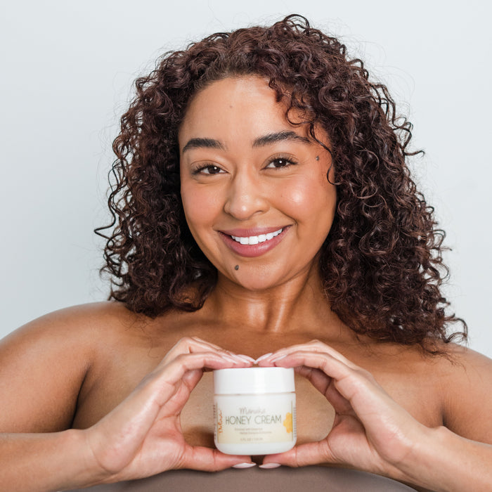 A woman holding a jar of Manuka Honey Cream in both her hands creating the shape of a heart.