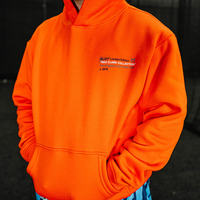 Youth model wearing orange Max Clark youth hoodie