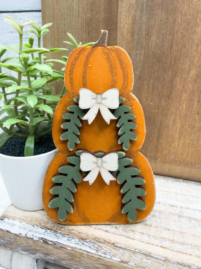 Hand-painted stacked pumpkin wood craft with layered bow and greenery details