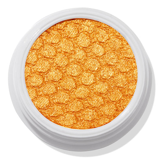 Montecito Super Shock Shadow by ColourPop shimmering in a bold metallic marigold-gold pan, embossed with a honeycomb texture, set in a round white pot against a clean white background.