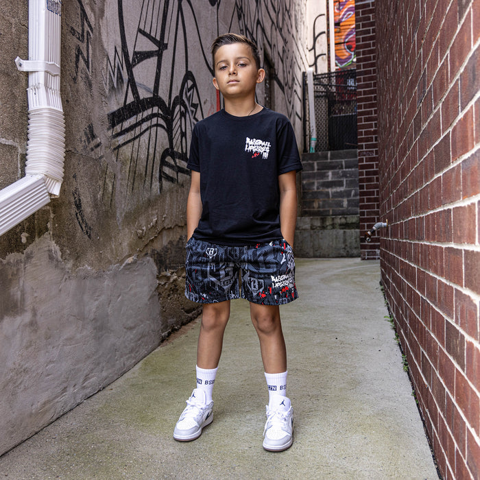 Youth model wearing black youth graphic tee with "Night Game Drip" design