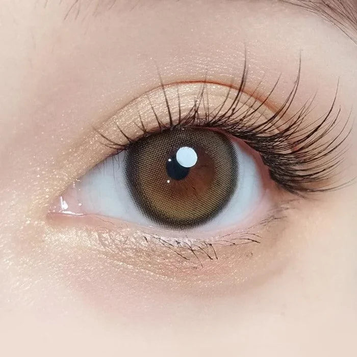 Macro shot of an eye wearing the Olola Blurring Brown prescription colour contact lens, showing the multi-colored detail and natural effect on dark brown eyes.