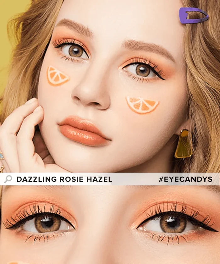 A young woman with hazel eyes, peach makeup, orange slice cheek art, purple hair clip, and yellow earrings wears Olola Dazzling 1-Day Rosie Hazel (10pk) color contacts. Text: “Dazzling Rosie Hazel” and “#EYECANDYS.” Brand: Olola.