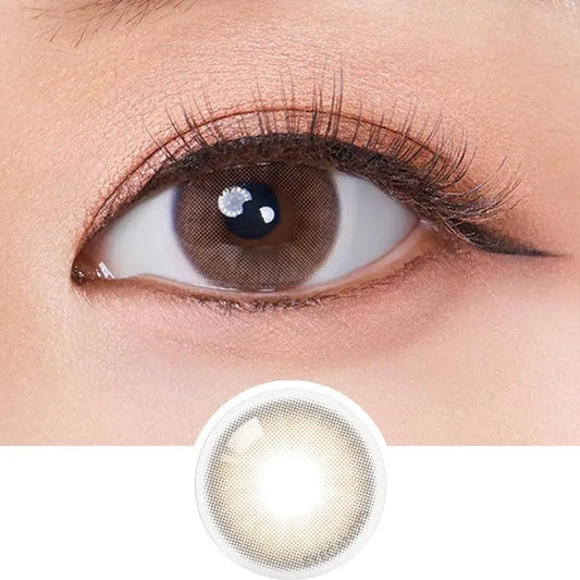 A close-up of a brown eye with long lashes, subtle eyeliner, and Olola Mellows Cotton Brown by Olola shows its stylish design and color—ideal for anyone seeking fashionable non-prescription contact lenses.