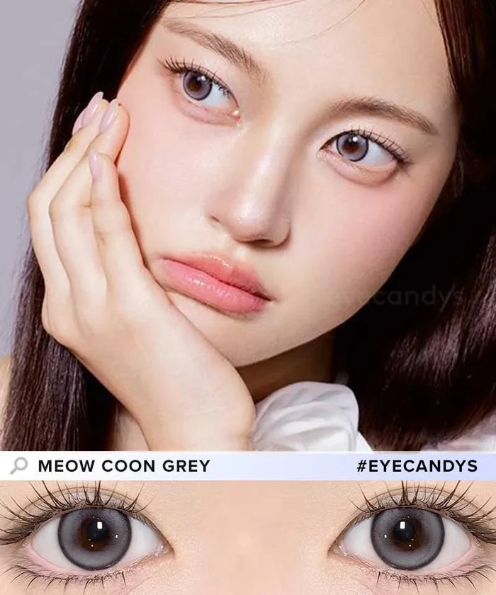 A woman with fair skin and straight dark hair rests her face on her hand, wearing Olola Meow Natural Coon Grey contacts by Olola. A close-up showcases the natural cat-eye look. Text reads "MEOW NATURAL COON GREY #EYECANDYS".