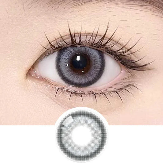 Close-up of a human eye wearing Olola Meow Vivid Burman Grey color contacts by Olola, with long eyelashes visible. A separate image below shows the unique grey pattern and shade designed for dark eyes.