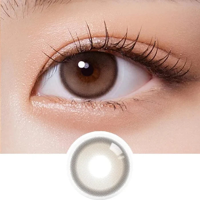 A close-up of a brown eye with long lashes wearing Olola Purity Shine 1-Day Taupe Brown color contact lens. Below, an Olola daily disposable lens from the 10-pack is shown on a white background.