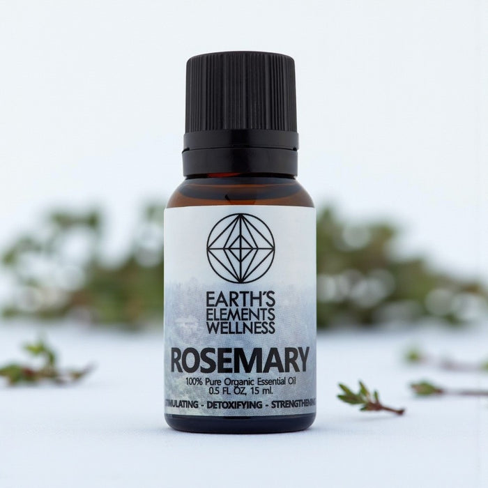 Bottle of Earth's Elements Wellness Rosemary essential oil with a blurred natural background